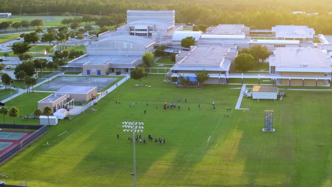 美国学校的体育教育。日落时分，学生们在学校体育馆进行体育锻炼，玩美式足球