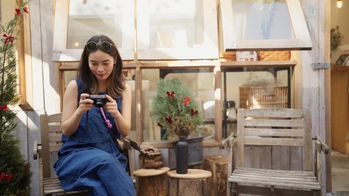 一名亚洲女性在咖啡店里看数码相机上的照片。