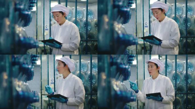 在一家工厂里，一名穿着实验室服装的女工拿着药片检查水瓶的生产。瓶装水生产中的HACCP体系