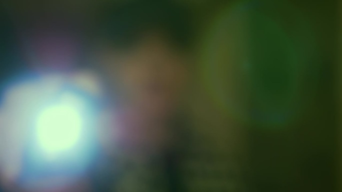 绿色的眩光，一个男人把手电筒照进相机镜头，漂亮的散景圈，背景为文字复制空间。
