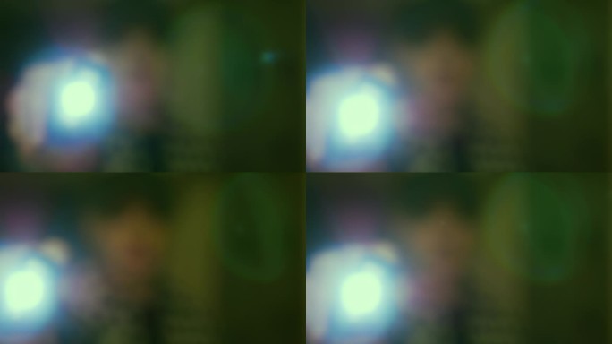 绿色的眩光，一个男人把手电筒照进相机镜头，漂亮的散景圈，背景为文字复制空间。