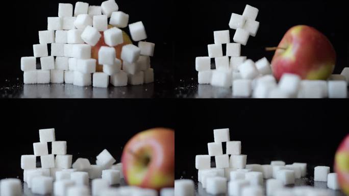 慢动作红苹果冲破白糖方块堆积的墙。选择健康的生活方式。不健康饮食的概念，糖尿病，肥胖，心脏病。甜食上