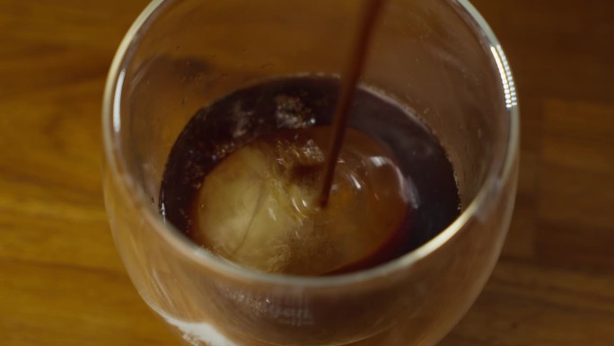 把煮好的咖啡倒在冰块上。做冰黑咖啡。加冰的冷咖啡。慢动作4k。把黑咖啡加冰倒进杯子里。美丽的烟雾。