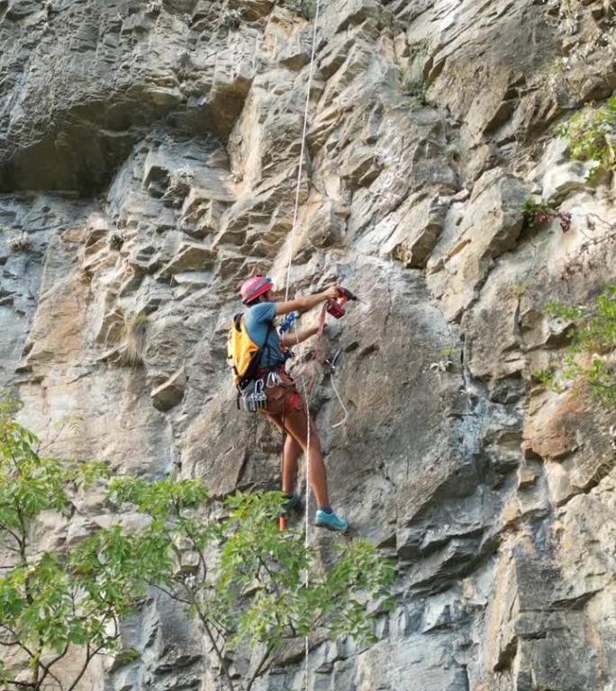 戴着红色头盔的攀登者用凿岩机和旋锤在攀登绳上开辟了一条新的攀登路线。