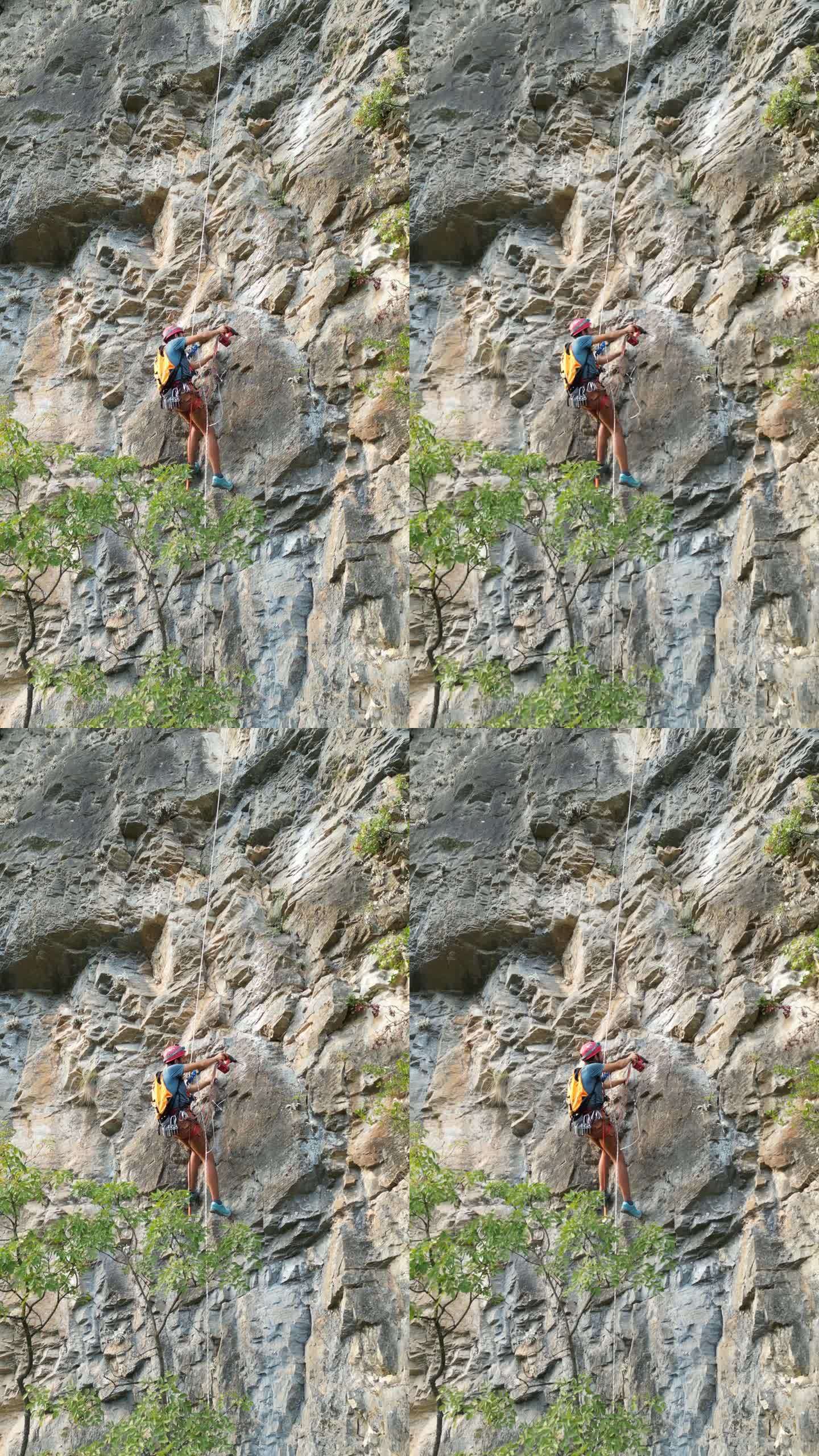 戴着红色头盔的攀登者用凿岩机和旋锤在攀登绳上开辟了一条新的攀登路线。