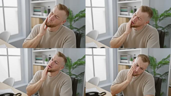 有胡子的白人男子在办公室工作时摸脸颊疼痛，显示出牙齿问题。