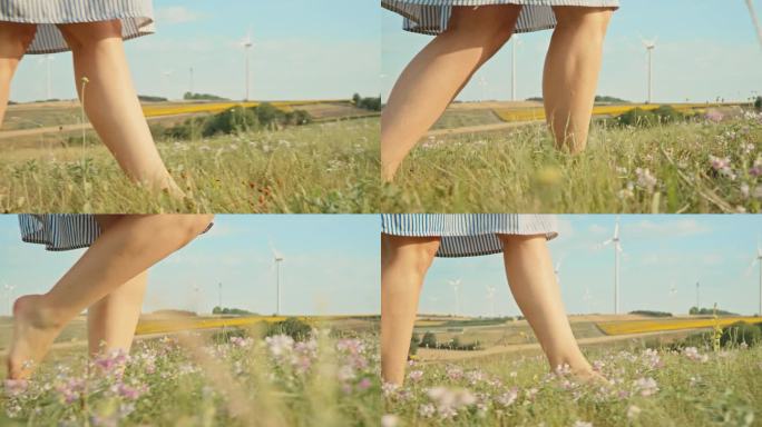 一个不知名的女人赤脚走在草地上，沿着风力涡轮机
