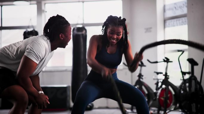 女人，私人教练和战斗绳在健身房锻炼，锻炼或肌肉耐力在健身动机。认真、活跃的女性，有耐力、有氧或高强度