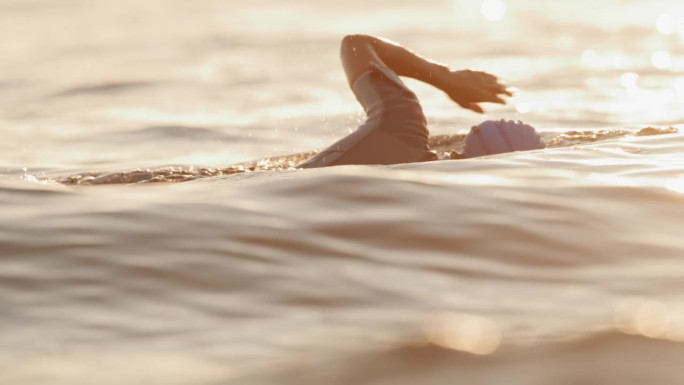 女子在日落度假期间在海洋游泳的慢镜头镜头。一个女人正在海里游泳。