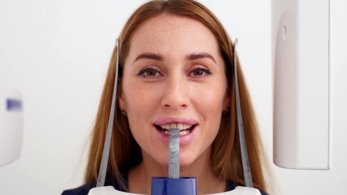 头部全景x光机拍摄的女性脸部特写。女病人站在牙科x光机前进行牙科x光摄影。拍摄下巴全景的女人。