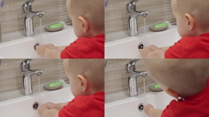 3岁的孩子正在学习洗手。可爱的小男孩在水槽里用洗手液洗手。