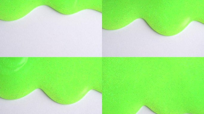 绿色的霓虹灯闪闪发光的五彩纸屑背景液体滴油漆颜色流下来的白色帆布。浅绿色闪闪发光的油漆滴在工艺纸墙上