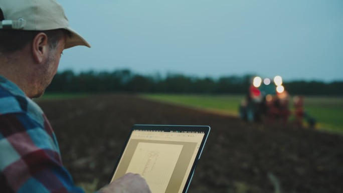 站在有机农场边用笔记本电脑工作的男女农学家