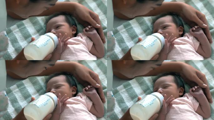 妈妈用爱给宝宝喂奶新生的宝宝用奶瓶喝奶新生的宝宝躺在床上喝奶可爱的宝宝在家里用爱喂奶新生的宝宝概念