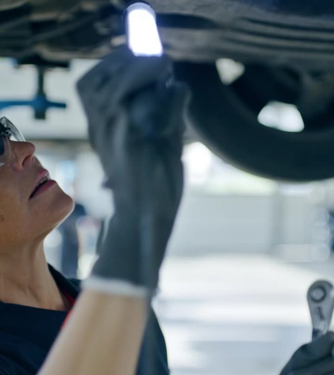 女机械师在汽车修理店修理汽车底盘