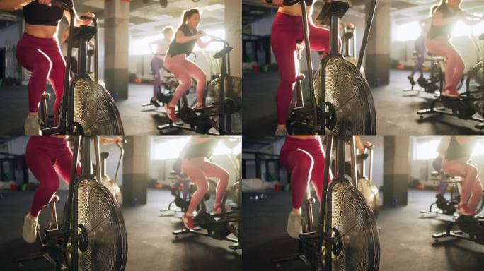 年轻的白人女运动员，在健身房的固定自行车机上一起锻炼