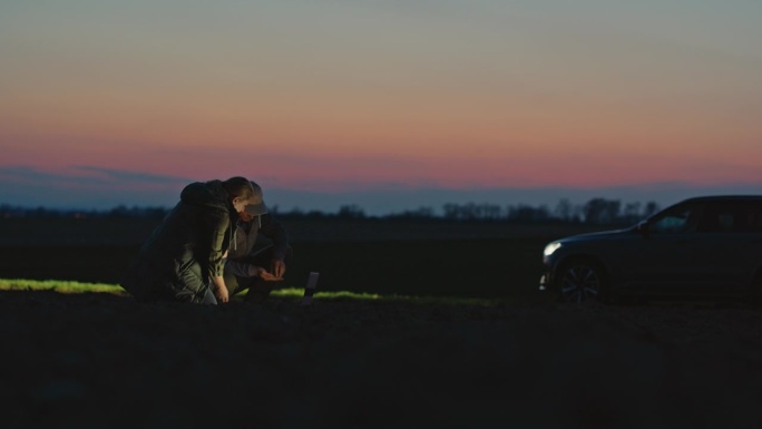 SLO MO锁定拍摄的女性和男性农民在日落时对着天空分析田地里的土壤