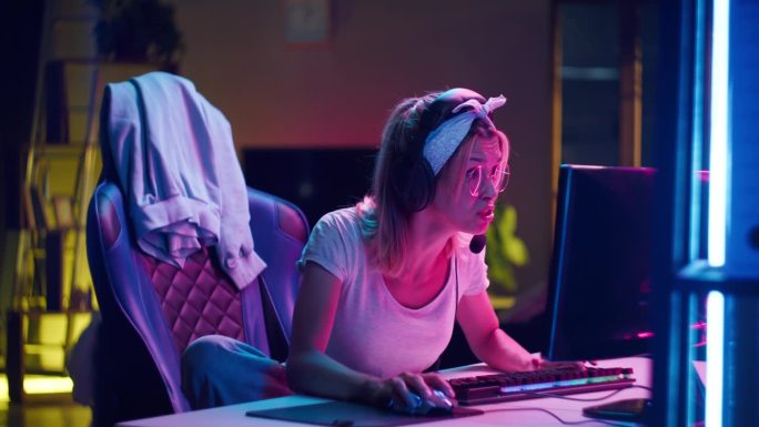 戴着耳机玩电脑游戏的年轻少女，失败者。心烦意乱的女玩家戴着眼镜，失败了艰苦的比赛，损失由于bug。电