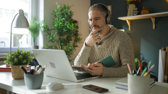 成熟的白人男子在家办公室用笔记本电脑学习在线课程