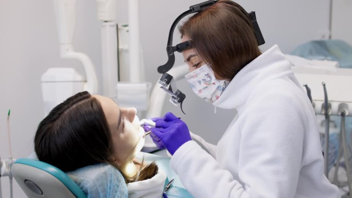 一位年轻女子正在一家现代化的牙科诊所接受治疗。牙科治疗的概念，美白，安装贴面和牙套，清洁口腔。