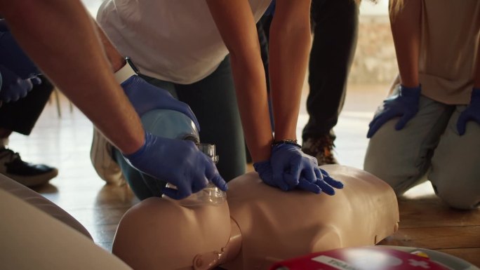 特写镜头:两个人使用人体模型和Ambu复苏袋进行心肺复苏术。女孩按在假人的胸前。实际培训。急救培训