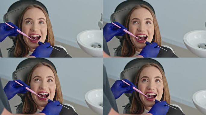 灿烂笑容评价:牙医用牙周探针对快乐的年轻女性患者