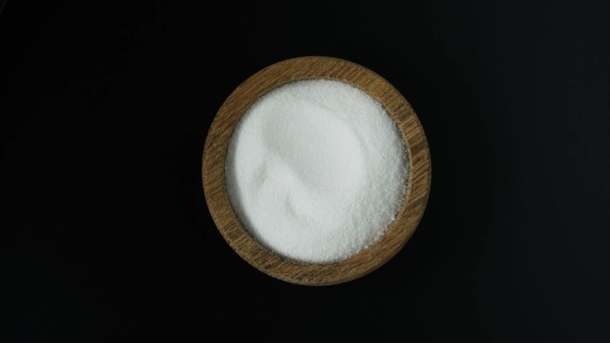木碗中的食品添加剂E575，俯视图。葡萄糖- δ内酯，也称为葡萄糖内酯。纯GDL，白色无臭结晶粉末。