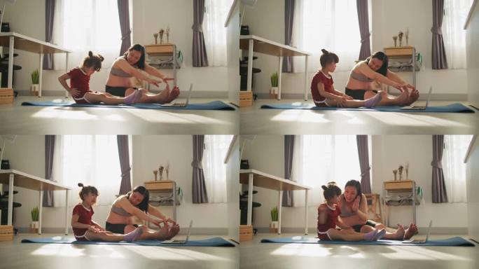 亚洲母亲和女儿在家里一起上在线瑜伽课
