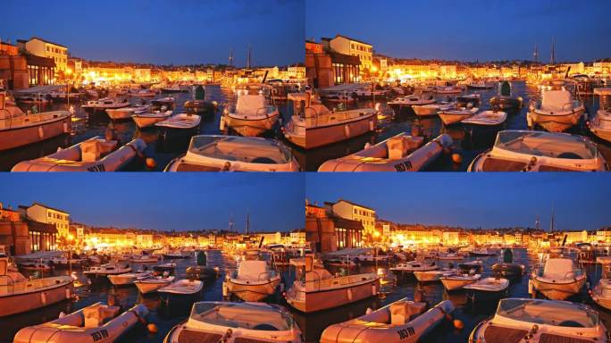 船只停泊在港口在照亮的老城黄昏的天空。罗维尼，伊斯特拉，克罗地亚。