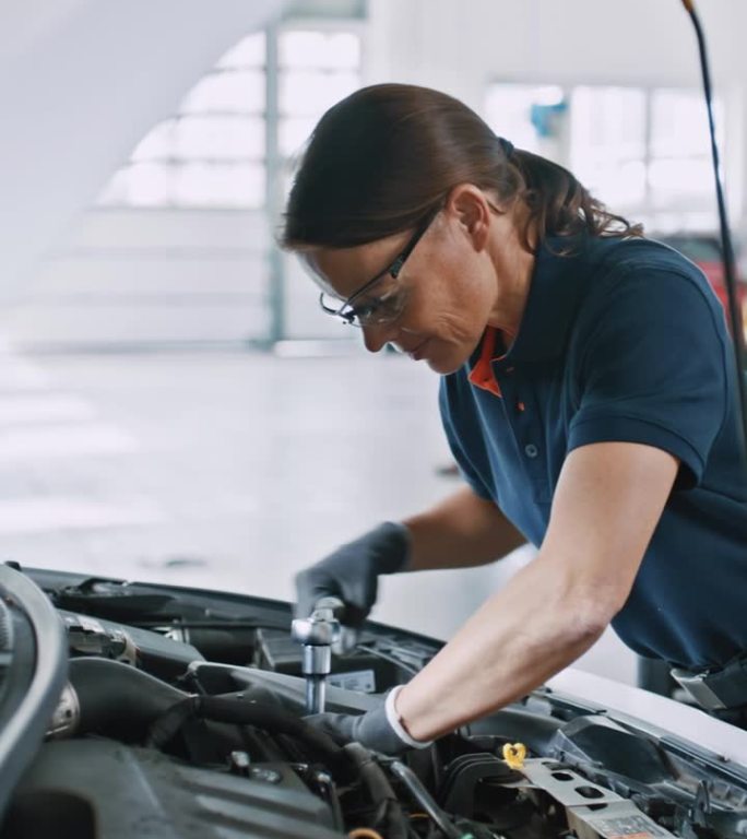 图为女机械师在汽车修理店修理汽车发动机