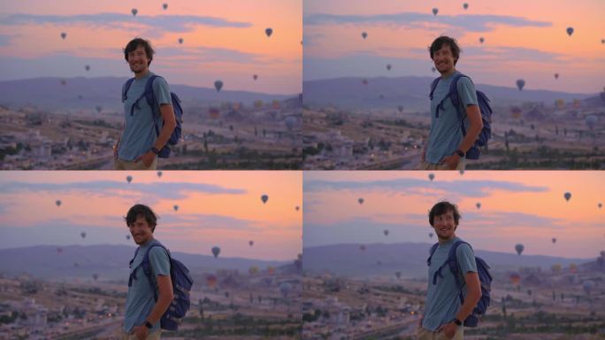 在土耳其卡帕多西亚，一名年轻的游客正在观看热气球。土耳其快乐旅行的概念。一个人站在山顶上欣赏美丽的景