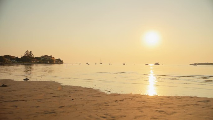 太阳反射在宁静的海面上，日落时船只在地平线上