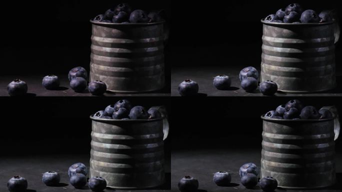新鲜成熟的蓝莓在黑色背景金属杯。低调。健康的素食。一束光穿过浆果