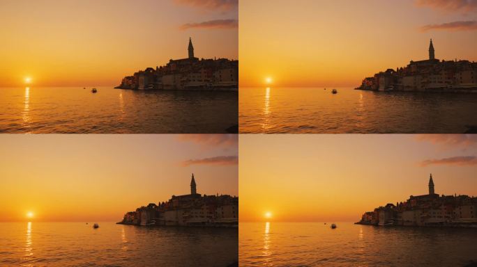 船在海上航行与古城背景在橙色的天空在日落。罗维尼，伊斯特拉，克罗地亚。