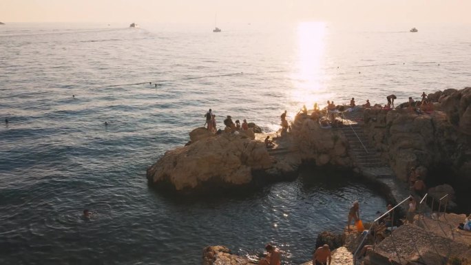 日落时海边岩石海岸线上的男女游客。Rovinj,克罗地亚