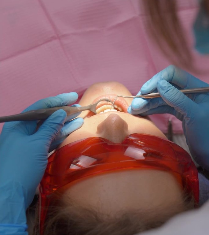 牙医非常仔细地检查并修复了他的女病人的牙齿