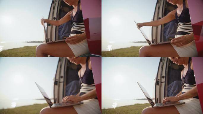 在湖边度假期间，女自由职业者在面包车上用笔记本电脑工作的镜头