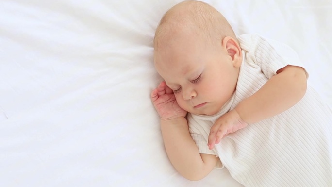 可爱的小新生儿睡觉，他的手交叉在他的脸颊，甜蜜的健康的婴儿睡在一个白色的婴儿床，一个地方的文字
