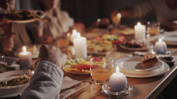 为了庆祝感恩节，一个大家庭吃了一顿节日晚餐，他们坐在节日的餐桌旁，享用美味的食物