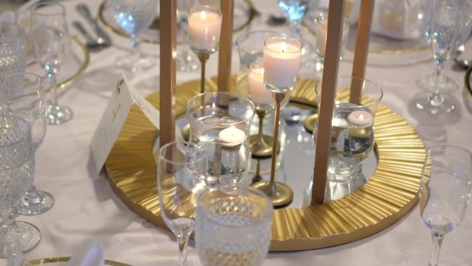 用优雅的玻璃器皿装饰的圆桌用于婚礼庆典，宴会桌为客人标识以数字四。