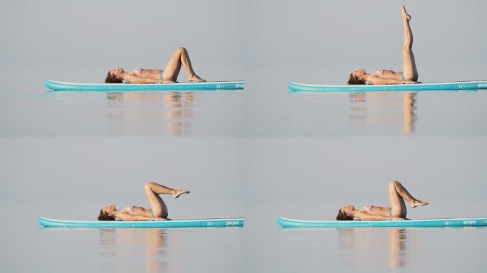 身穿比基尼的女子在海上冲浪板上进行放松练习的慢镜头
