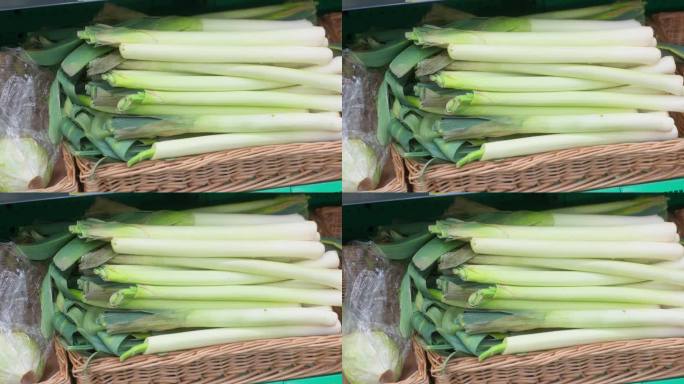 在一个阳光明媚的日子里，当地农贸市场里，绿色的韭菜整齐地排列在柳条篮子里