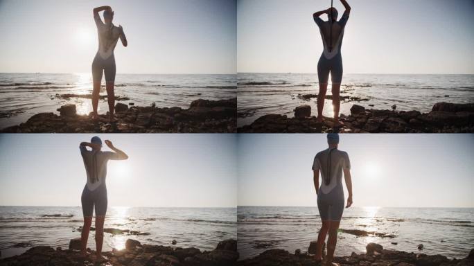 在日落时，穿着潜水服的女人在岩石上走向大海的慢镜头。游泳准备。
