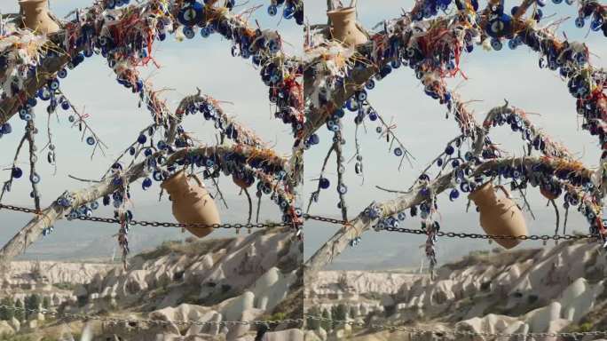 垂直视频。高山上的喂鸽人，背景是峡谷中的一座古城。鸽子聚集在一棵装饰着土耳其护身符的树下，以抵御邪恶