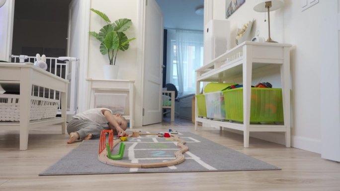 可爱的小男孩在玩木制铁路玩具，小朋友在房间的地板上玩电动火车玩具