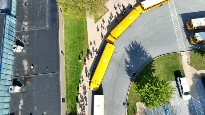 美国学生放学后走向公共汽车的鸟瞰图。秋天的黄色校车。