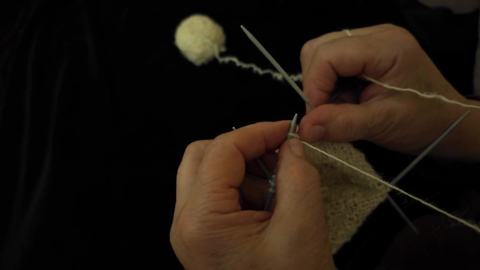 祖母用传统的矛制作袜子，使用天然羊毛，以纱线编织为背景
