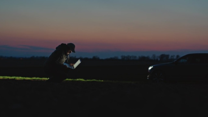 在黄金时段，农艺师用手提电脑对着天空检查田地土壤