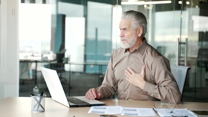 一位头发花白、胡子花白的老商人在办公室工作时突发心脏病。
