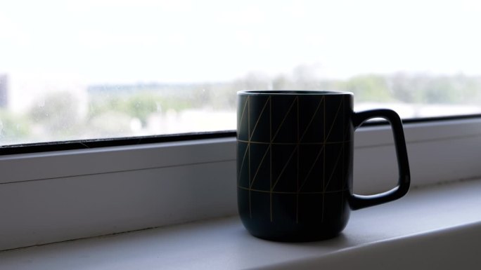 剪影，站在窗边的窗台上喝一杯热咖啡或茶